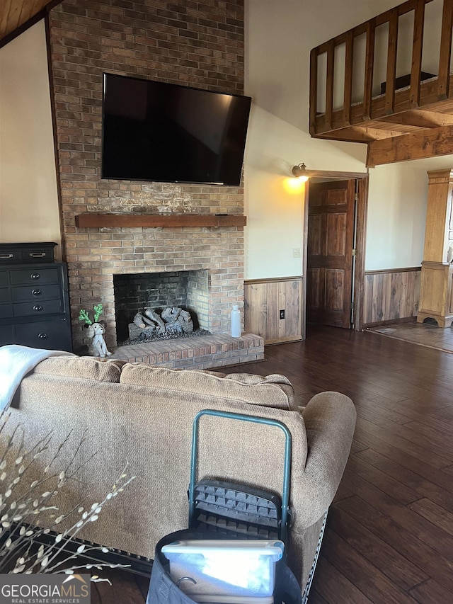 living room featuring dark hardwood / wood-style floors, wooden walls, and a fireplace