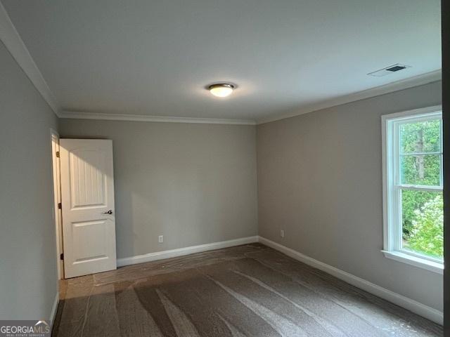 unfurnished room with crown molding, a healthy amount of sunlight, and carpet flooring