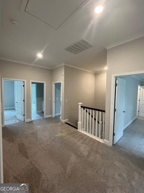 spare room with visible vents, carpet, baseboards, ornamental molding, and attic access
