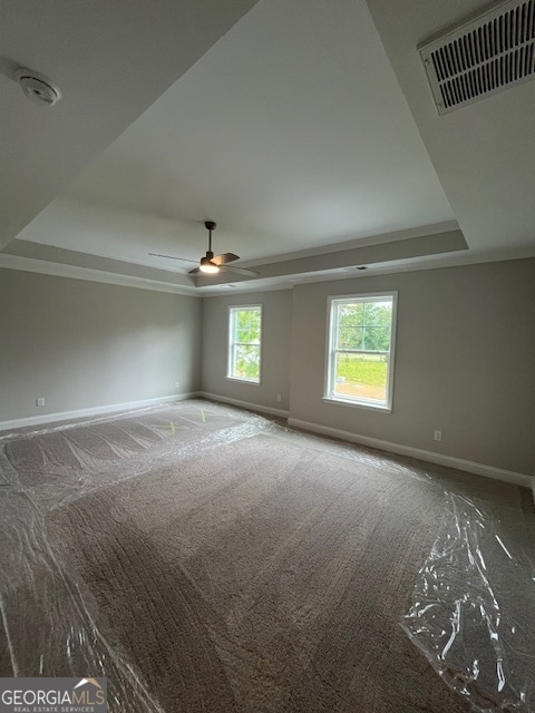 spare room featuring carpet flooring, a tray ceiling, and ceiling fan