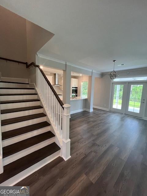 staircase featuring hardwood / wood-style flooring, plenty of natural light, an inviting chandelier, and crown molding