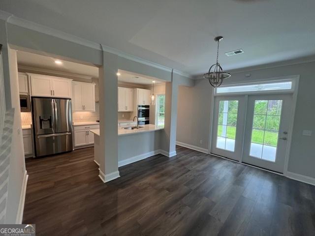 kitchen featuring hanging light fixtures, an inviting chandelier, appliances with stainless steel finishes, white cabinetry, and dark wood-type flooring