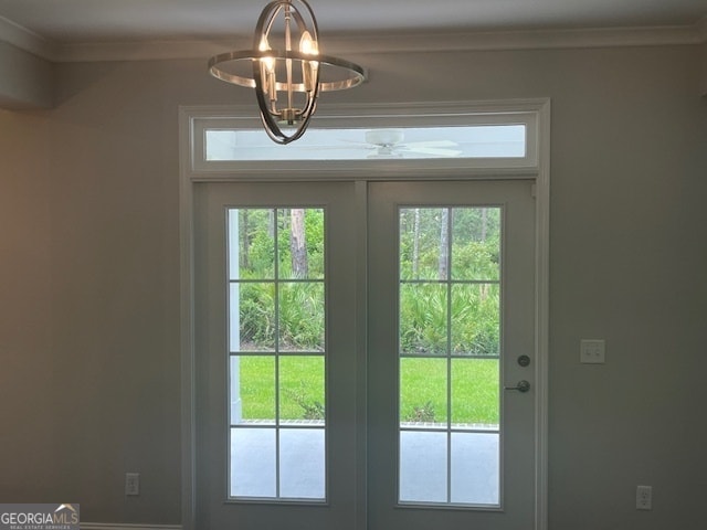 entryway with crown molding, a wealth of natural light, and a notable chandelier