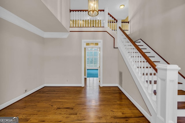 stairway with a high ceiling, a notable chandelier, and dark hardwood / wood-style floors