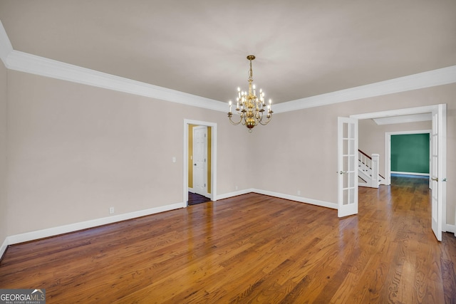 spare room with dark wood-type flooring, ornamental molding, and a chandelier