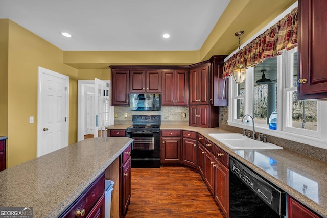 kitchen with pendant lighting, dark wood-type flooring, light stone counters, sink, and black appliances