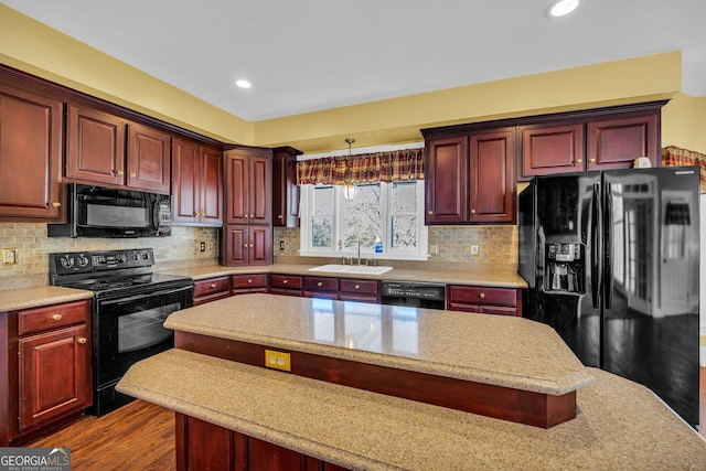 kitchen with decorative light fixtures, dark hardwood / wood-style floors, black appliances, sink, and tasteful backsplash