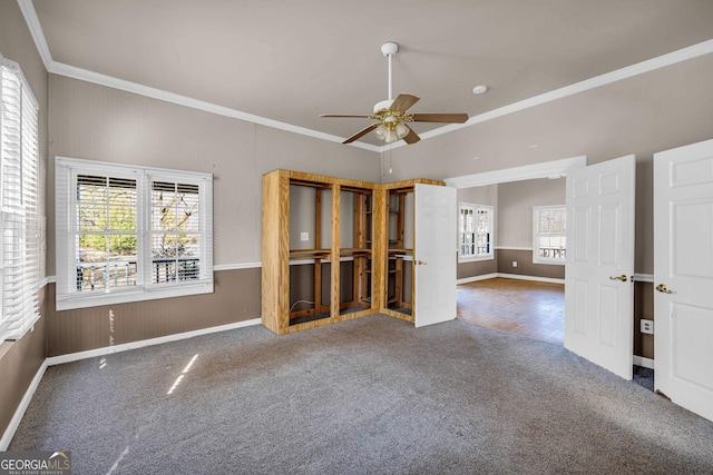 carpeted spare room with plenty of natural light, ceiling fan, and ornamental molding