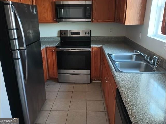 kitchen with stainless steel appliances, light tile flooring, and sink