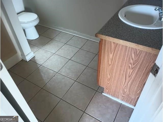 bathroom featuring toilet, tile flooring, and vanity