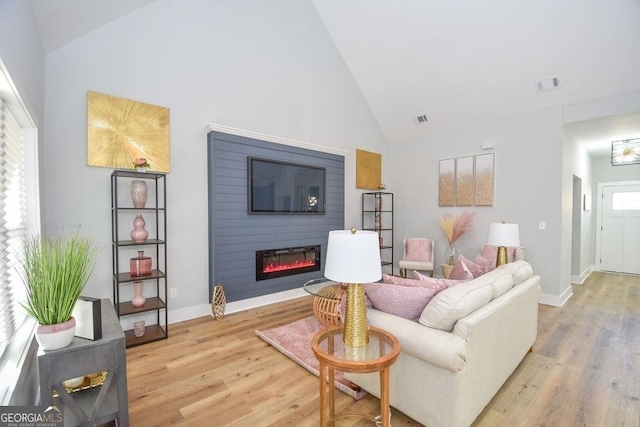 living room featuring light hardwood / wood-style flooring, high vaulted ceiling, and a fireplace