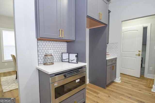 kitchen with light hardwood / wood-style floors, gray cabinetry, and tasteful backsplash