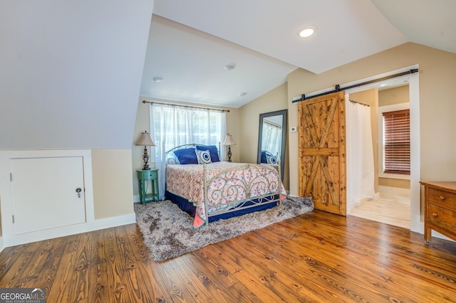 228 Harris Rd, Jackson, GA 30233 - bedroom with a barn door, wood-type flooring, and vaulted ceiling