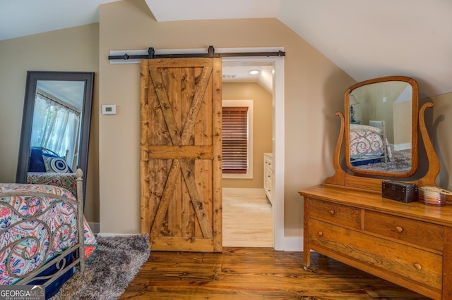 228 Harris Rd, Jackson, GA 30233 - bedroom featuring wood-type flooring, a barn door, and lofted ceiling