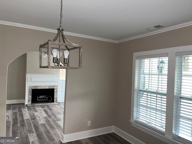 unfurnished living room featuring a high end fireplace, dark wood-type flooring, a chandelier, and crown molding