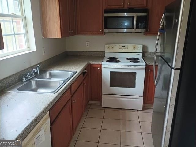 kitchen featuring appliances with stainless steel finishes, sink, and light tile flooring