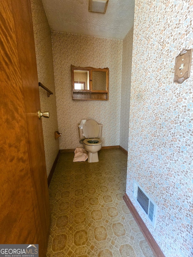 bathroom with a textured ceiling, toilet, and tile floors