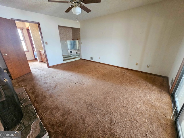 unfurnished bedroom with connected bathroom, a textured ceiling, ceiling fan, and light colored carpet