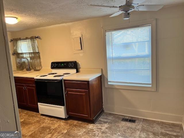 kitchen with ceiling fan, sink, electric range, and a textured ceiling