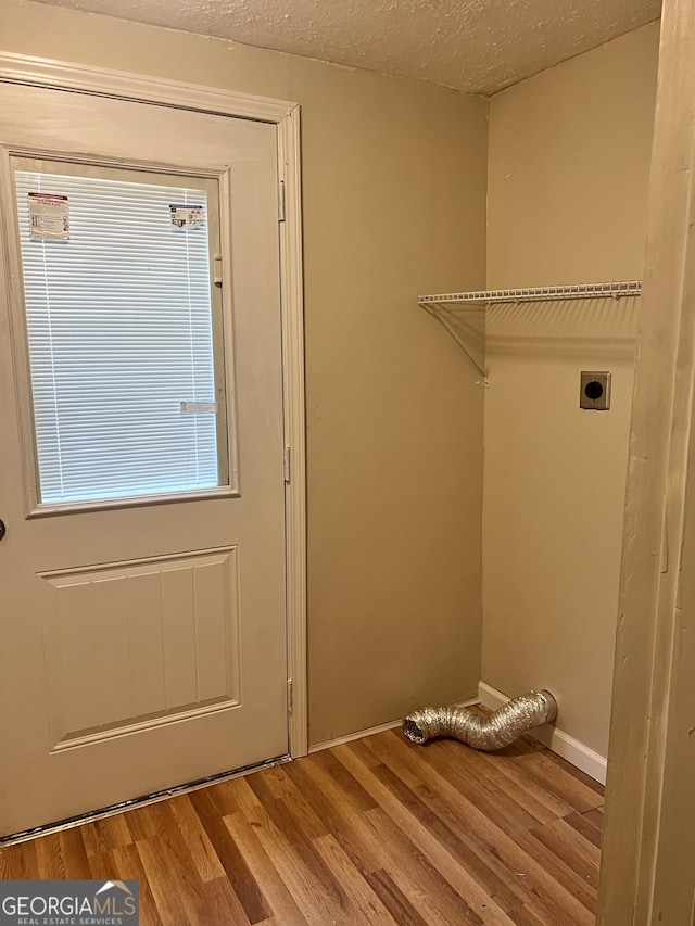 clothes washing area featuring a textured ceiling, hardwood / wood-style floors, and electric dryer hookup