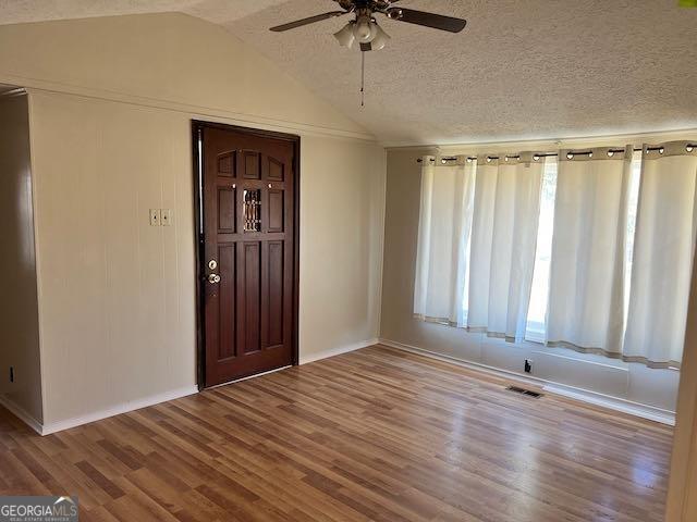 foyer entrance with lofted ceiling, ceiling fan, a textured ceiling, and hardwood / wood-style floors