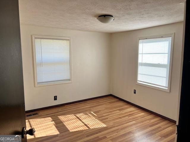 empty room featuring a textured ceiling and light hardwood / wood-style floors