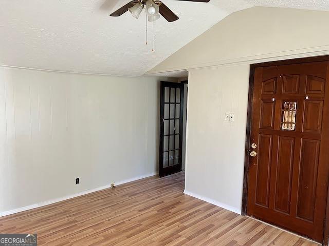 foyer entrance featuring ceiling fan, a textured ceiling, light hardwood / wood-style flooring, and lofted ceiling