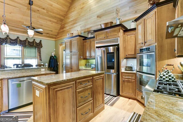 kitchen with light stone countertops, pendant lighting, appliances with stainless steel finishes, ceiling fan, and light wood-type flooring