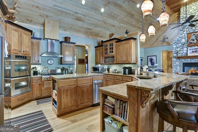 kitchen with hanging light fixtures, a fireplace, wooden ceiling, kitchen peninsula, and a kitchen breakfast bar