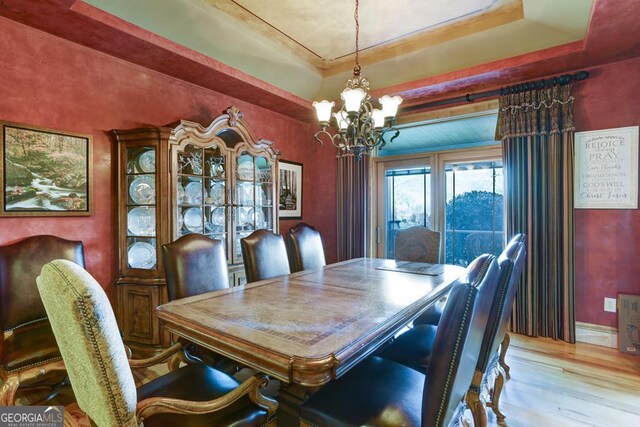 dining room with an inviting chandelier, light wood-type flooring, and a tray ceiling