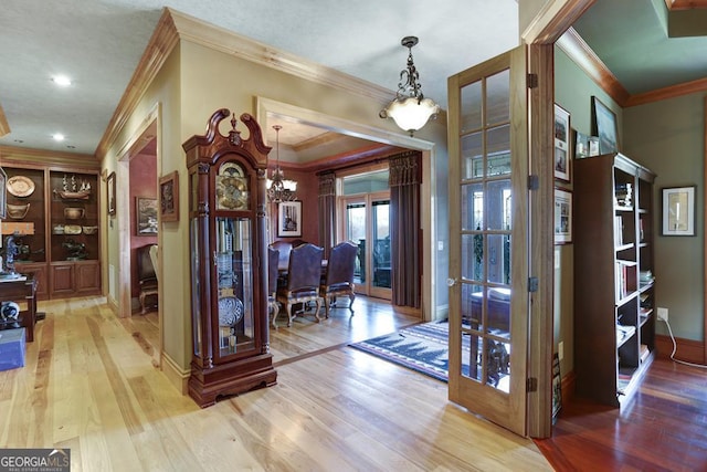 entryway featuring crown molding, an inviting chandelier, and light wood-type flooring