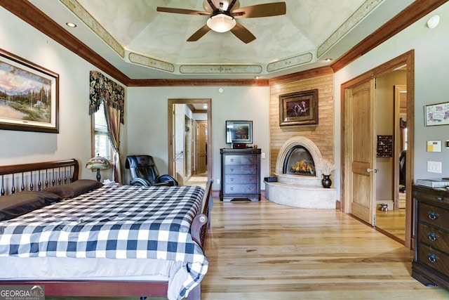 bedroom with crown molding, a tray ceiling, ceiling fan, and light hardwood / wood-style floors