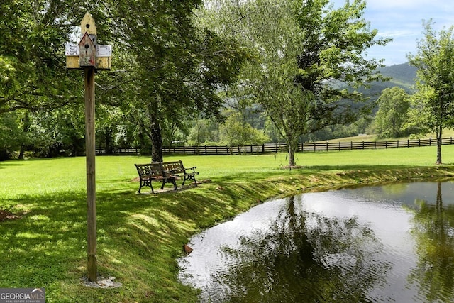 surrounding community with a water and mountain view and a lawn