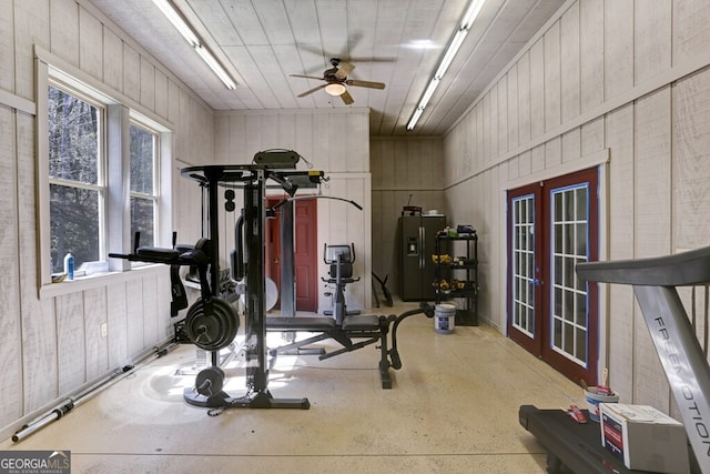 workout area featuring ceiling fan, wood walls, and french doors