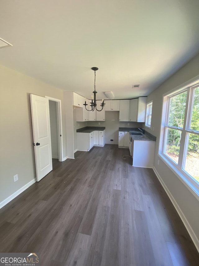 kitchen featuring pendant lighting, sink, white cabinetry, dark hardwood / wood-style floors, and a notable chandelier