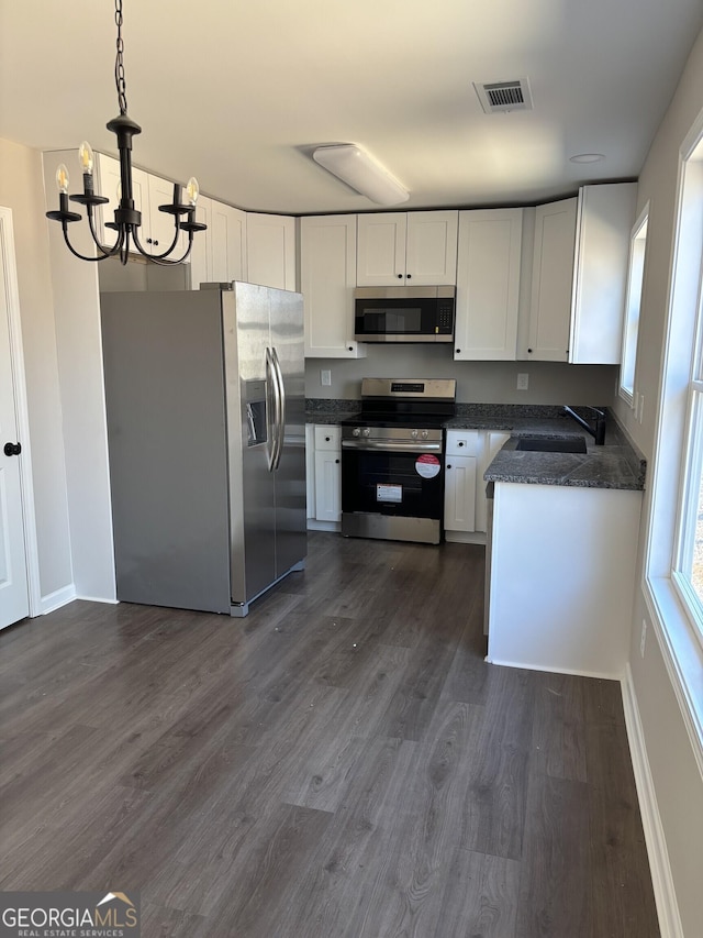 kitchen with white cabinets, dark countertops, dark wood-type flooring, pendant lighting, and a sink