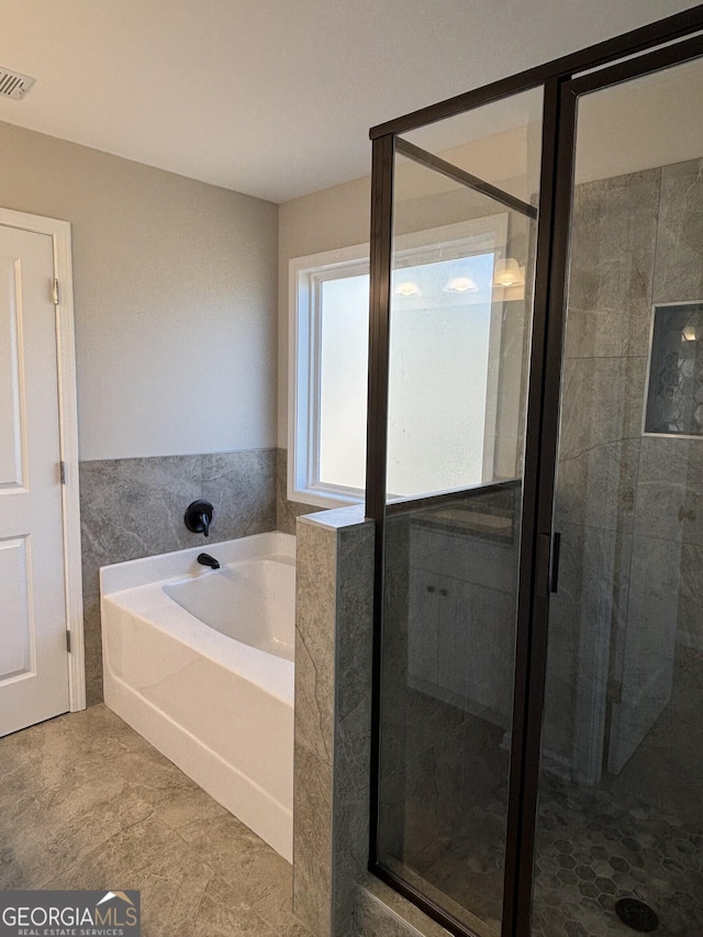 full bathroom with visible vents, a stall shower, a garden tub, and tile walls