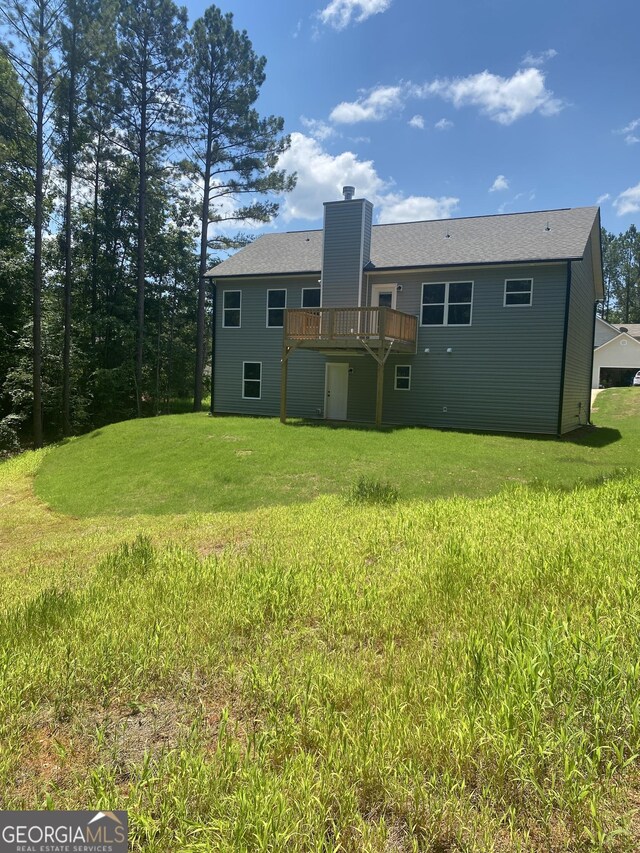 rear view of house featuring a deck, a yard, and a chimney