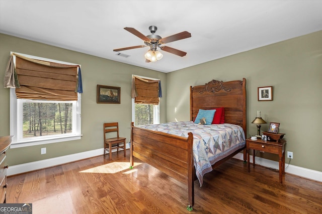 bedroom featuring ceiling fan, dark hardwood / wood-style flooring, and multiple windows