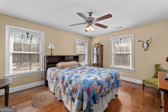 bedroom with dark hardwood / wood-style flooring, ceiling fan, and multiple windows