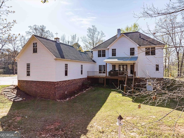 rear view of property featuring a wooden deck and a lawn