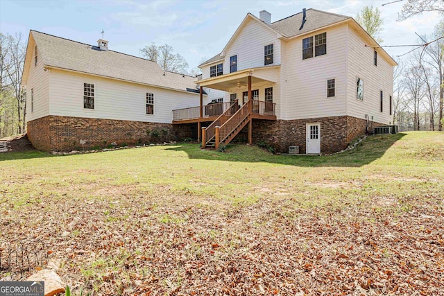 rear view of property with a wooden deck and a lawn