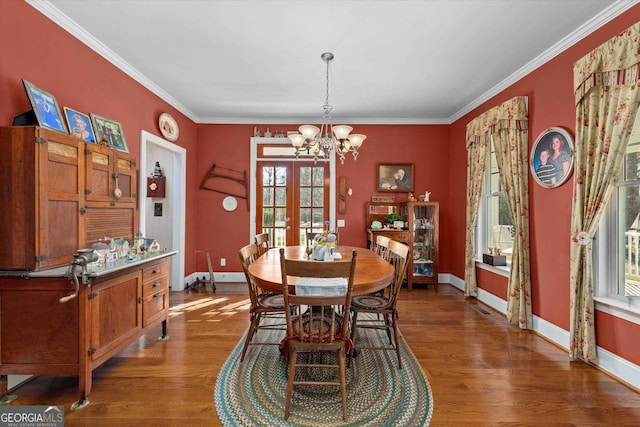 dining room featuring ornamental molding, dark hardwood / wood-style flooring, french doors, and an inviting chandelier