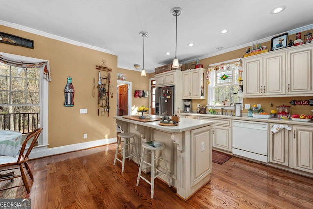 kitchen with high quality fridge, hanging light fixtures, white dishwasher, hardwood / wood-style flooring, and a center island