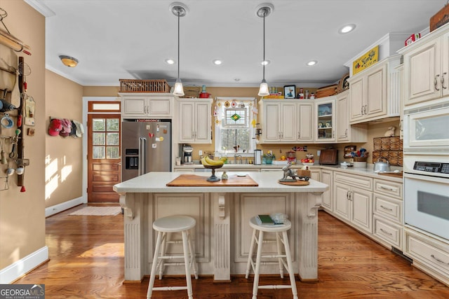 kitchen featuring a center island, pendant lighting, light hardwood / wood-style floors, and white appliances