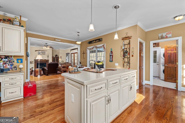 kitchen featuring ceiling fan, crown molding, white cabinetry, pendant lighting, and light wood-type flooring