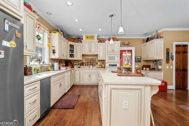 kitchen with a center island, hardwood / wood-style floors, stainless steel appliances, ornamental molding, and pendant lighting