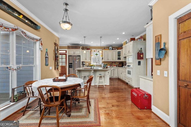 dining room with light wood-type flooring and ornamental molding