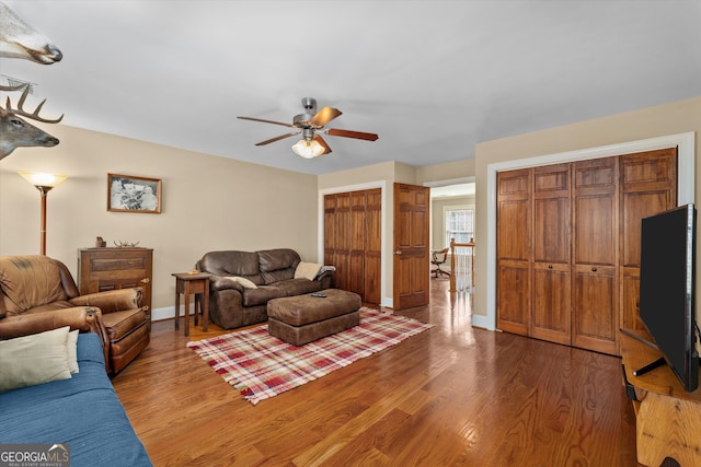 living room with dark hardwood / wood-style flooring and ceiling fan