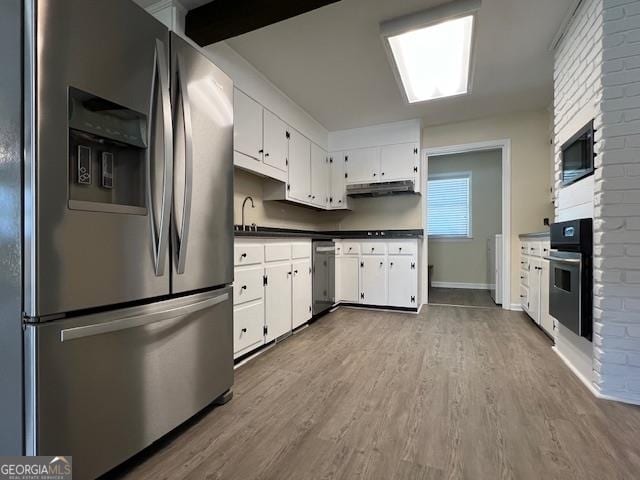 kitchen featuring brick wall, light hardwood / wood-style floors, white cabinets, and appliances with stainless steel finishes